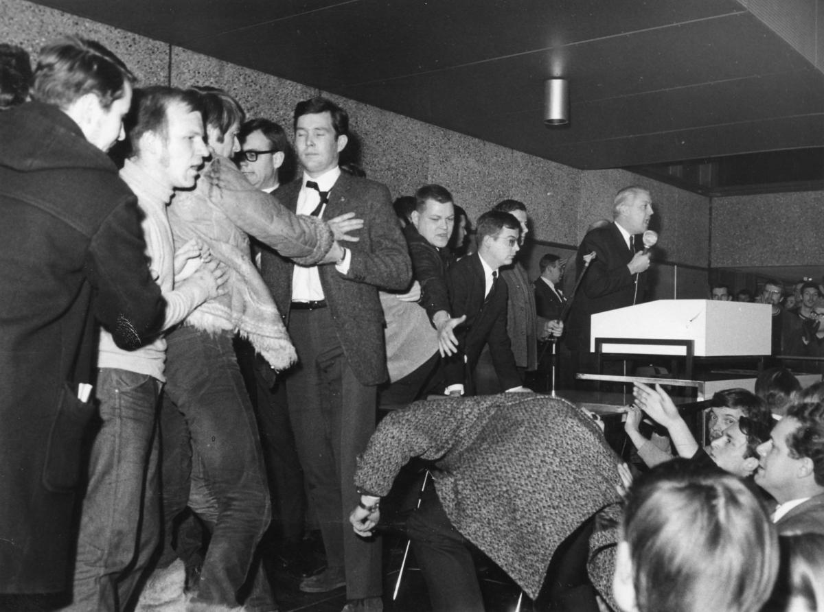 16.12.1968: Linksradikale Studenten versuchen in der Mensa der CAU das Podium zu stürmen, auf dem Minister Gerhard Stoltenberg (am Mikro) über Hochschul-und Wissenschaftspol. spricht. - Foto: KN-Archiv/Friedrich Magnussen